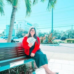 a woman holding money on a bench